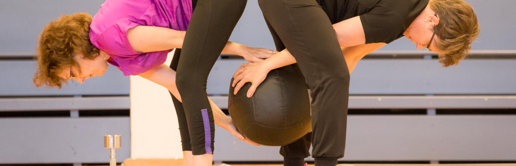 Två kvinnor tränar med en boll